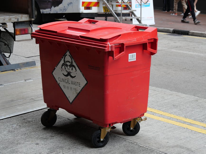 A collection of various plastic containers and fuel cans placed outdoors on the ground, including blue, yellow, and red fuel cans, some with labels or caps visible. There are also black hoses coiled n